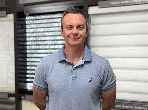 A man with his arms folded behind his back, smiling for a photo